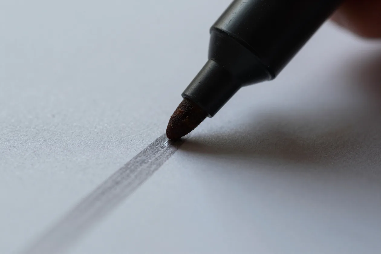 Macro of a highlighter dragging a wet stripe across a printed page